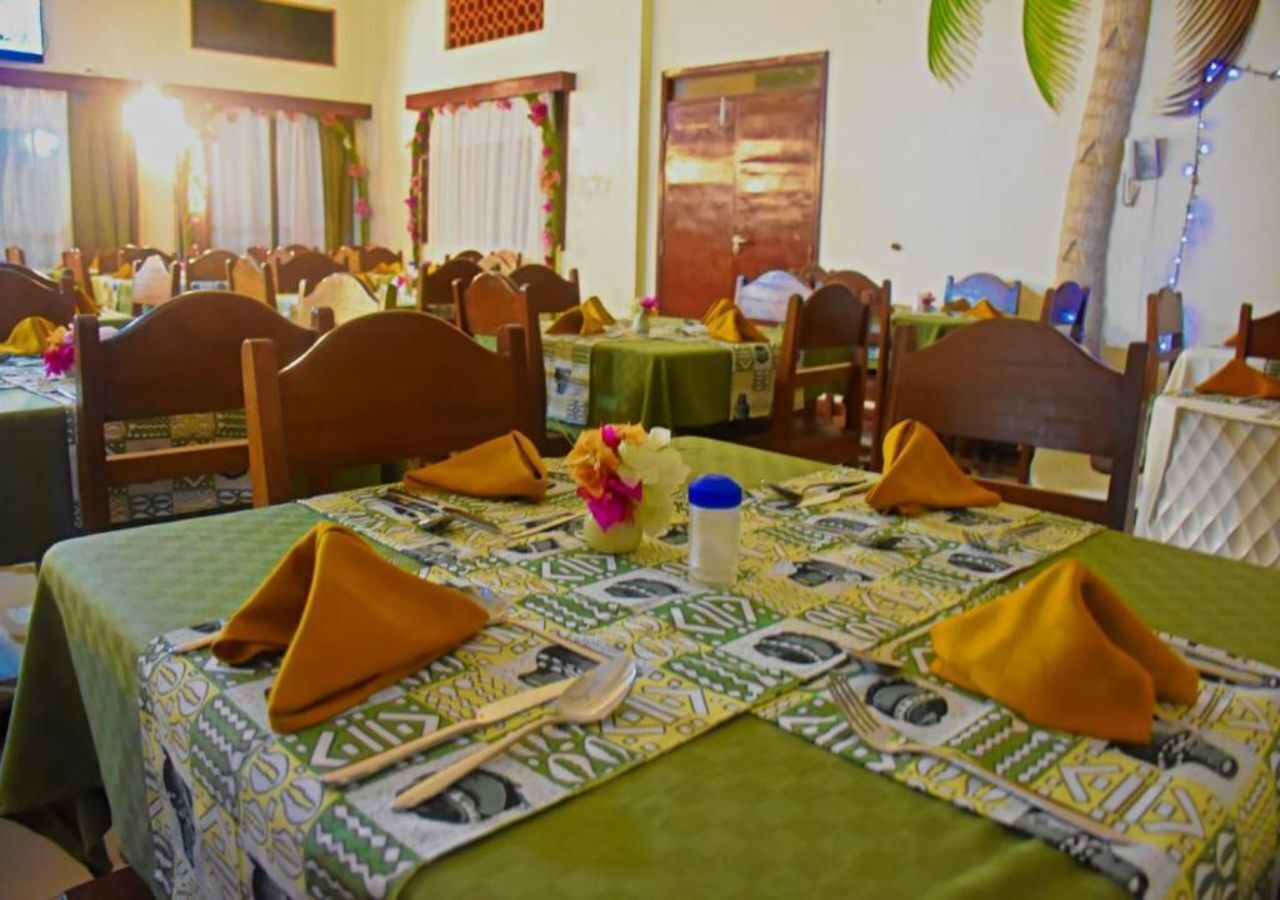 A restaurant with tables set for dining, featuring green tablecloths and yellow napkins.
