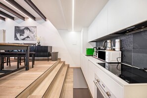 Et moderne køkken med hvide skabe, en mikrobølgeovn og kaffemaskine.