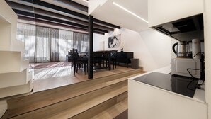 Eine moderne Küche mit Essbereich, Holzboden und einer Treppe.