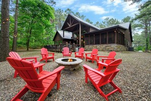 Eine Lodge mit Kamin aus Stein und rotem Adirondack-Stuhl-Anordnung darumherum.