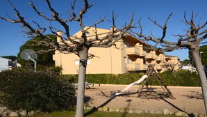 Un edificio residencial con un patio arenoso, un columpio y árboles sin hojas.