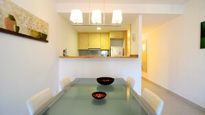 Comedor con mesa de vidrio, dos cuencos y sillas blancas.