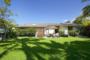 A single-story house with a tiled roof, a covered patio with outdoor furniture, and a well-maintained lawn. - Breathtaking Panoramic Ocean Views, Crystal Blue Pool, Hot Tub, BBQ Grill! (Kailua-Kona)