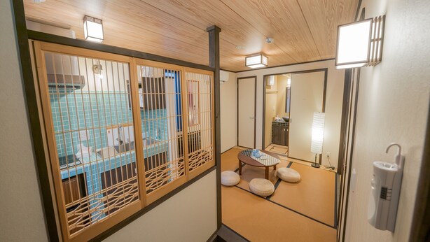 A traditional Japanese-style room with tatami flooring, a shoji screen, a wooden ceiling, and a large mirror.