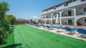 A hotel with a swimming pool, multiple balconies, and a green lawn. - Brinswick Private Villa complex (Laganas, Zakynthos)