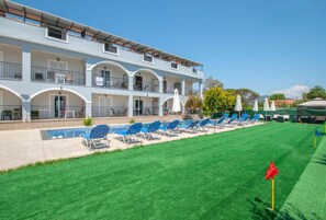 Un hotel con piscina, varios balcones y un césped bien cuidado.