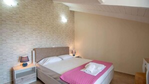 A bedroom with a bed, nightstands, a lamp, and a chair. - Brinswick Private Villa complex (Laganas, Zakynthos)