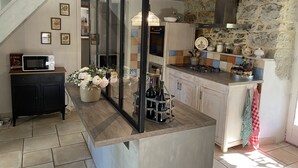 Ett kök med en vägg av sten, en mikrovågsugn, en kaffemaskin och en vas med blommor.