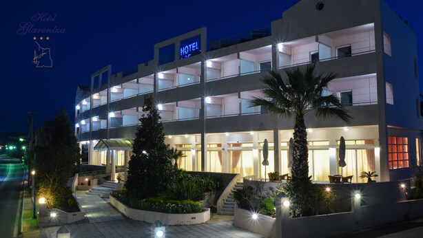 Un hotel de varios pisos con un llamativo letrero 'HOTEL', zona de estar al aire libre y caminos bien iluminados.