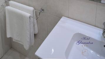 A bathroom with a white sink, a mirror, a towel rack, and a shower enclosure.