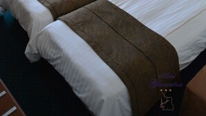Una habitación de hotel con dos camas, una silla, una mesita y una lámpara.
