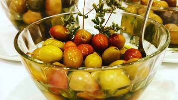 A glass bowl filled with various fruits and a sprig of herbs.