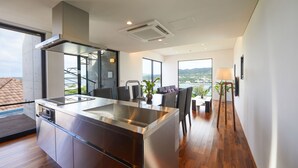A modern kitchen with a stainless steel island, built-in appliances, and large windows offering a view of the city.