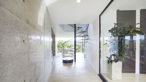 A modern interior with a glass wall, a spiral staircase, and a potted plant.