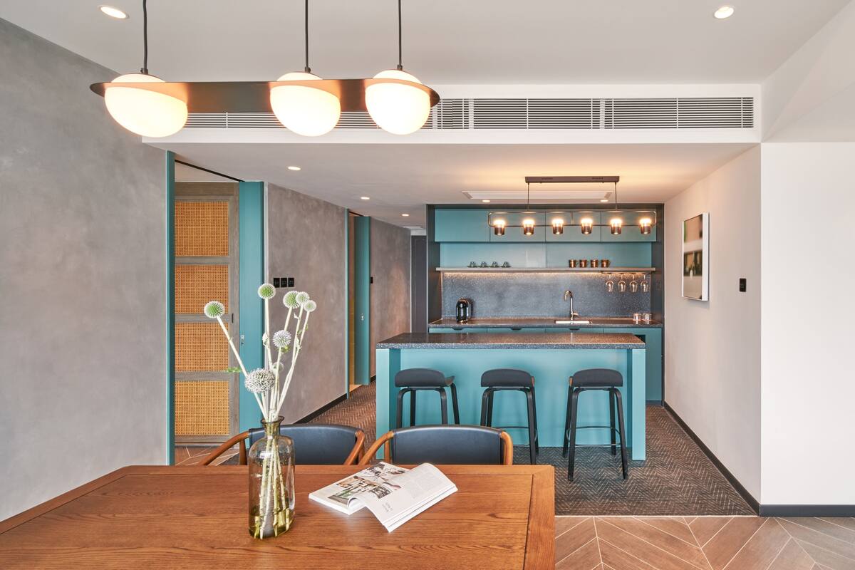 Una cocina moderna con barra, mesa de comedor de madera y taburetes de bar.