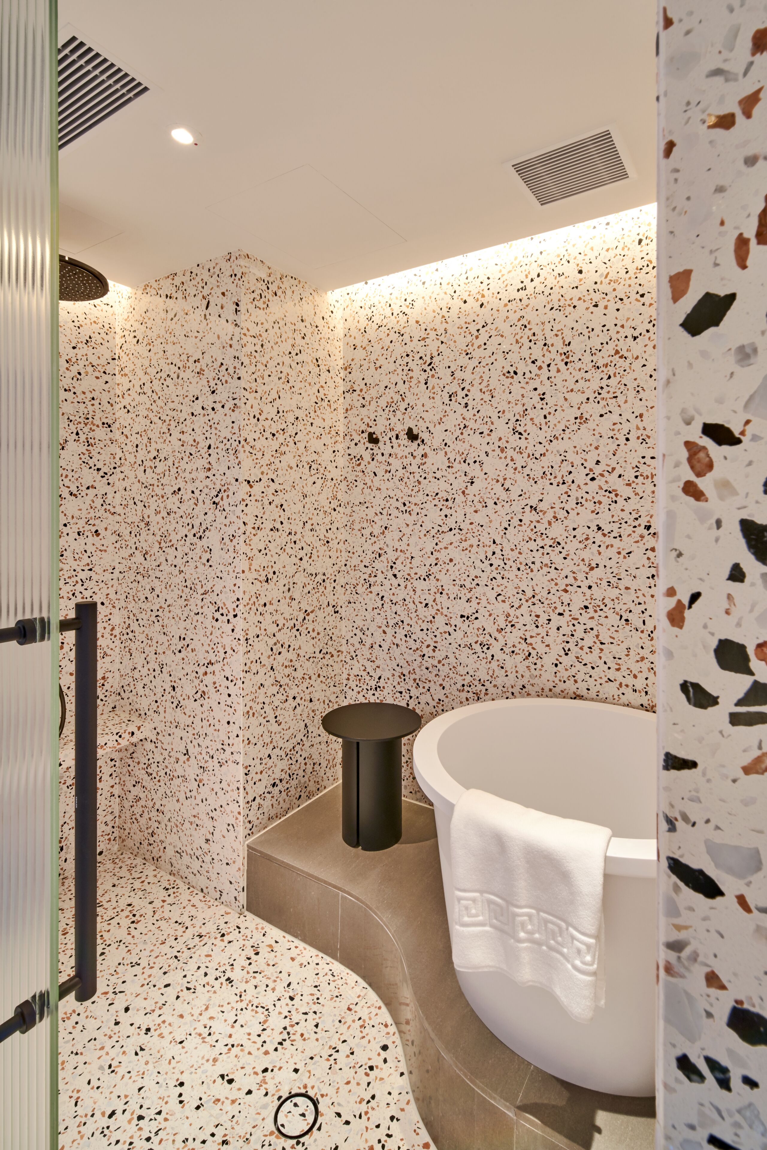 Un bagno moderno con una vasca da bagno freestanding, un appendi asciugamani e una zona doccia.