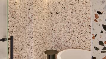 Un bagno moderno con una vasca da bagno freestanding, un appendi asciugamani e una zona doccia.