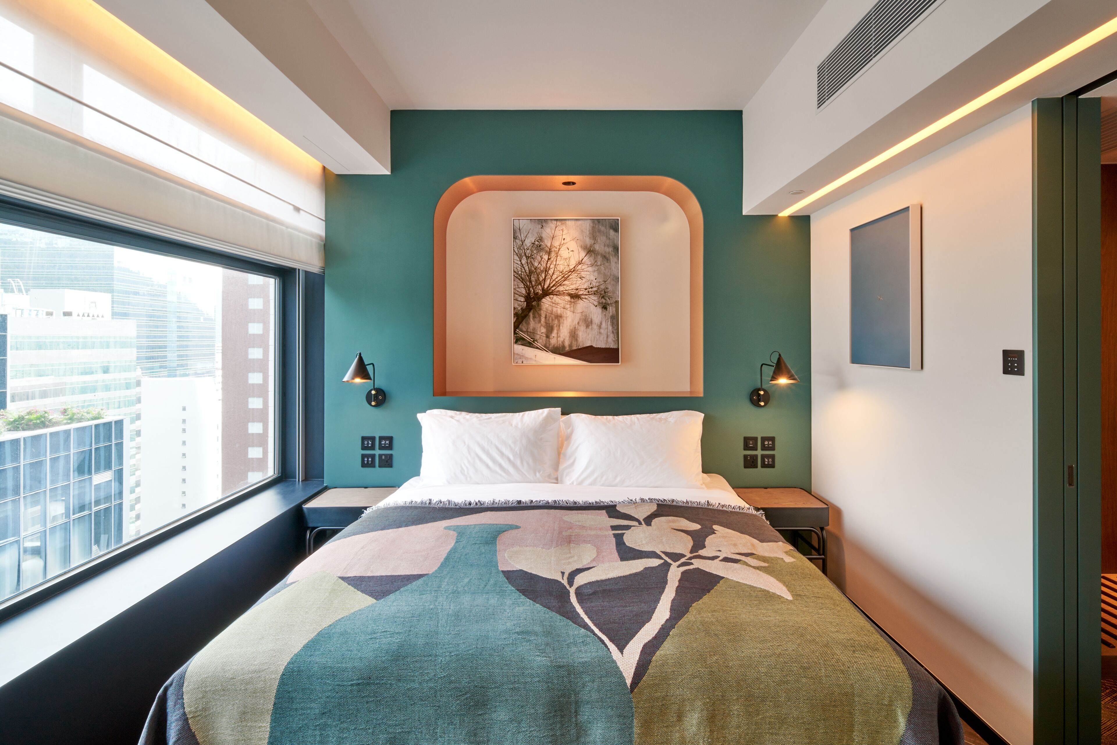 Une chambre d’hôtel moderne avec un grand lit, une vue sur la ville et un tableau au mur.