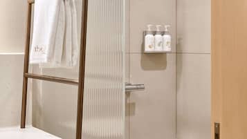 Een moderne badkamer met een douche, een handdoekhouder en een plank met toiletartikelen.