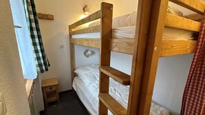 Kerrossängyllä varustettu huone, jossa on pieni yöpöytä ja seinään kiinnitetty valaisin.