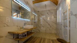 Ein modernes Badezimmer mit Marmorboden, Holzwaschbecken und einer Duschkabine.
