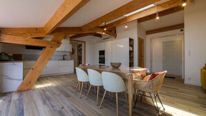 Eine moderne Küche mit weißen Schränken, Holzboden und einer Essecke mit Stühlen und Tisch.