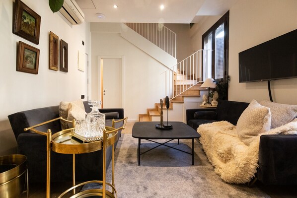 Una sala de estar moderna con una escalera, un televisor de pantalla plana y una mesa de centro.