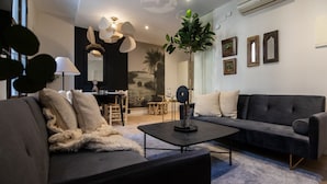 A modern living room with a dark grey sofa, a coffee table, and a dining area with a wooden table and chairs. - CASA TAMARIT DUPLEX (Barcelona)