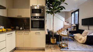 A modern kitchen with built-in appliances, a dining area with a sofa and coffee table, and a staircase leading to an upper level. - CASA TAMARIT DUPLEX (Barcelona)
