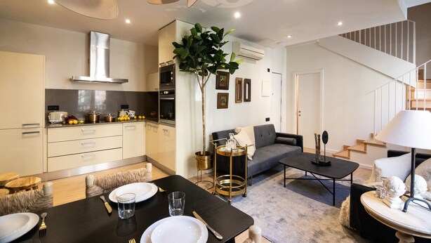 A modern kitchen with a dining area, a sofa, and a staircase. - CASA TAMARIT DUPLEX (Barcelona)