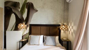 A bedroom with a bed, two bedside tables, a radiator, and a wall-mounted air conditioner. - Panoramic Sea Views, Pool, Garden, BBQ, TableTennis, Playground, Hammock (Chania)
