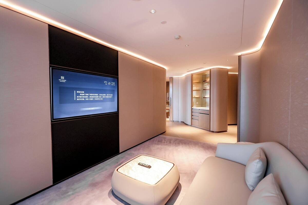 A modern hotel room with a flat-screen TV mounted on the wall, a plush sofa, and a minimalist design.