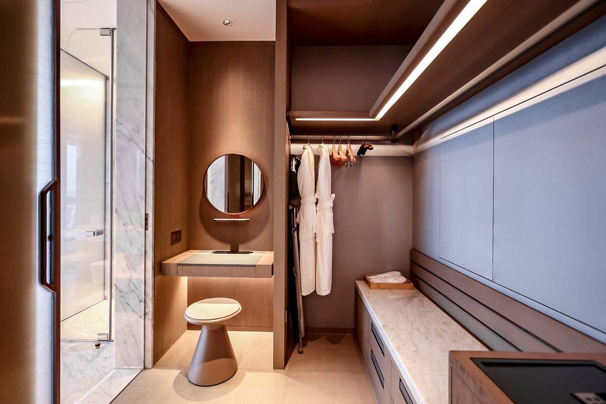 A modern bathroom with a marble sink, a round mirror, and a shower area.