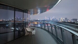 A modern balcony with a curved glass railing, offering a view of a city skyline at night. - Guangzhou Xanadu Hotel, Vignette Collection by IHG (Guangzhou)