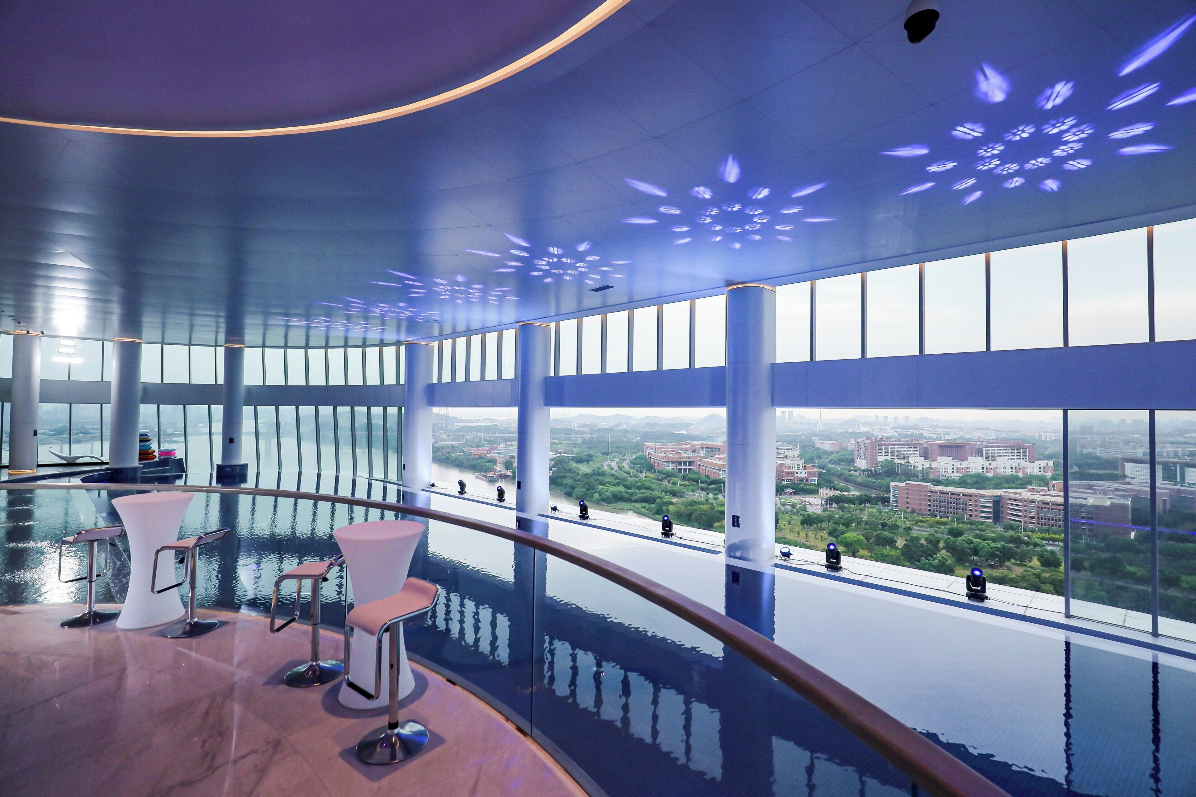 A modern interior with a curved balcony, large windows, and a view of the cityscape.