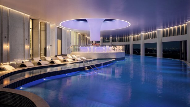 A modern indoor swimming pool with lounge chairs and a central bar area. - Guangzhou Xanadu Hotel, Vignette Collection by IHG (Guangzhou)