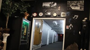 A hallway with a vending machine, a mannequin, and various wall decorations including clocks and a sign for Artist Housing Inc. - Artist Housing - Hostel (Los Angeles)