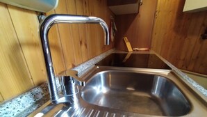 Een roestvrijstalen spoelbak met een moderne kraan in een keuken in houtstijl.