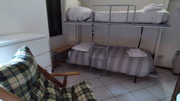 Une chambre avec un lit superposé, un lit simple et une chaise.