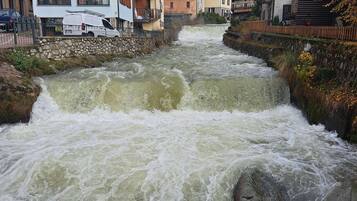 Ein Fluss mit steiniger Uferböschung, umgeben von mehrstöckigen Gebäuden mit Balkonen, manche mit Bepflanzung.