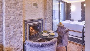 Un cuarto acogedor con chimenea de piedra, una mesa de comedor con sillas y vistas a la ciudad a través de amplios ventanales.