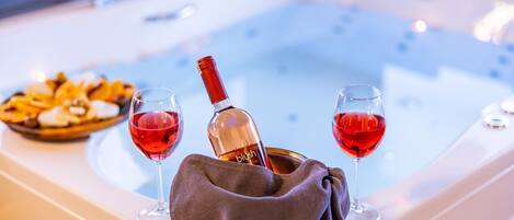 Un jacuzzi con dos copas de vino tinto y una botella de vino.
