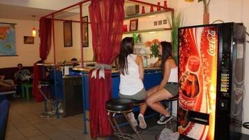 A bar area with a red canopy, a Coca-Cola vending machine, and stools.