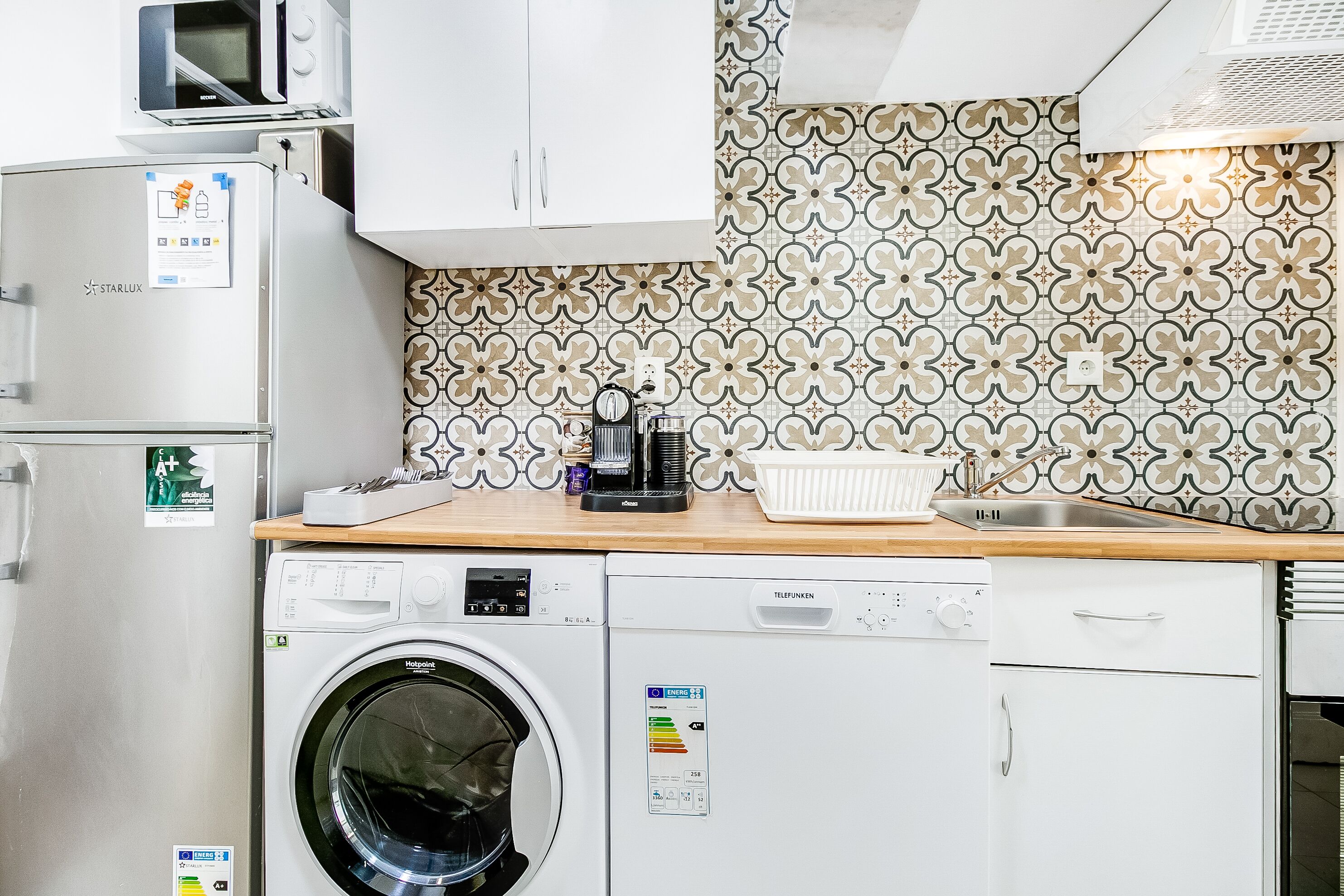 A compact kitchen with a washing machine, a microwave, and a coffee maker on the counter.