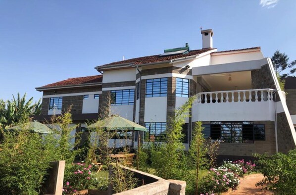 A two-story house with a balcony, surrounded by greenery and a garden. - ViVa Gardens (Gatundu)