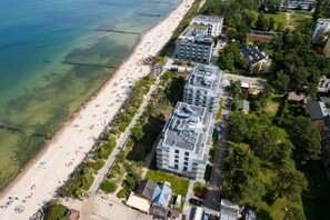 An aerial view of a coastal area with a beach, buildings, and greenery. - Mielno | Piastów 11A | Comfortable Apartment | Terrace and air conditioning (Mielno)