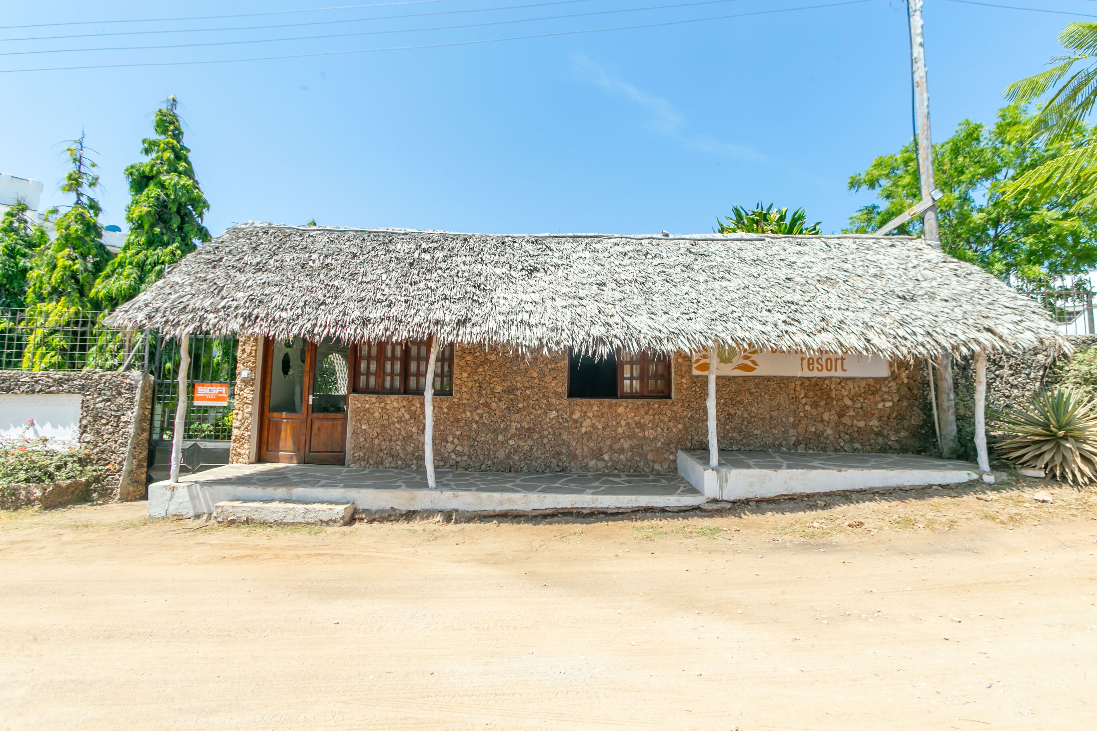Un petit bâtiment rustique, doté d’un toit de chaume, d’une porte en bois et d’une enseigne indiquant qu’il s’agit d’un complexe hôtelier.