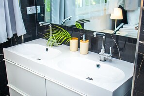 Un baño moderno con dos lavamanos, un espejo grande y una planta en maceta.