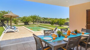 Un espace extérieur aménagé pour les repas, avec une piscine, des chaises longues et une vue sur le paysage environnant.