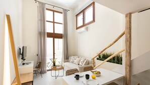 A modern, well-lit room with a dining table set for breakfast, a sofa, and a staircase with wooden railings. - Palm Residences (Kassandra)
